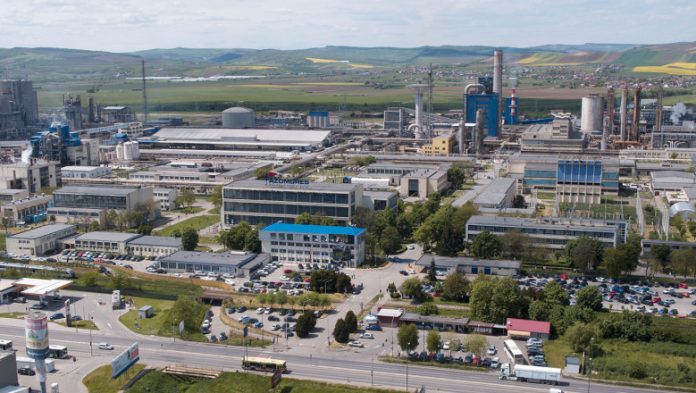 Vedere panoramică a combinatului de îngrășăminte chimice Azomureș din Târgu Mureș, evidențiind halele de producție, furnalele și infrastructura industrială sub un cer parțial noros.