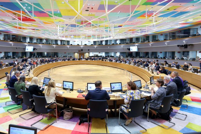 Reuniune oficială a Consiliului Agricultură și Pescuit la Bruxelles, cu delegați așezați la o masă circulară mare, sub un tavan colorat, discutând bugetul pentru agricultură al UE.