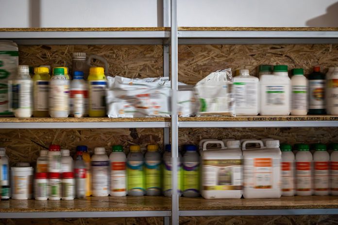 Flacoane si recipiente cu substante chimice periculoase pe rafturi in timpul unui control produse fitosanitare in ferme.