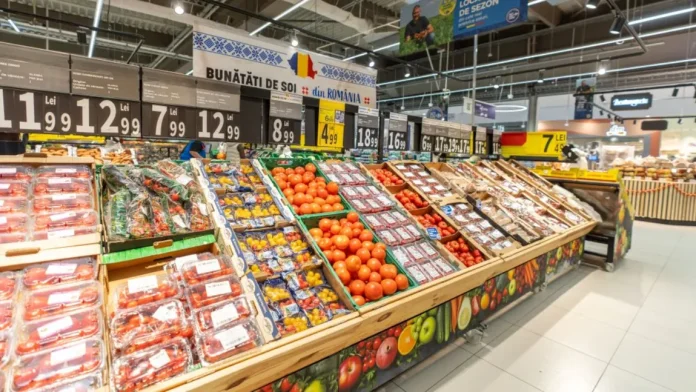 Rafturi mari pline cu legume românești, roșii de mai multe soiuri, ardei și verdețuri sub bannerul Bunătăți de soi din România în magazin.