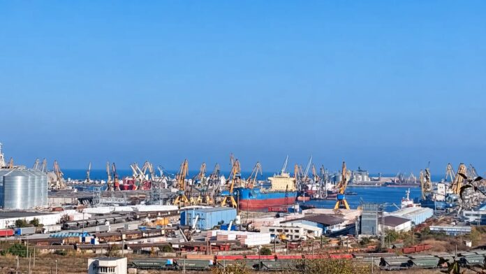 Vedere de sus cu Portul Constanța, macarele portuare, silozuri de cereale și nave cargo ancorate la Marea Neagră